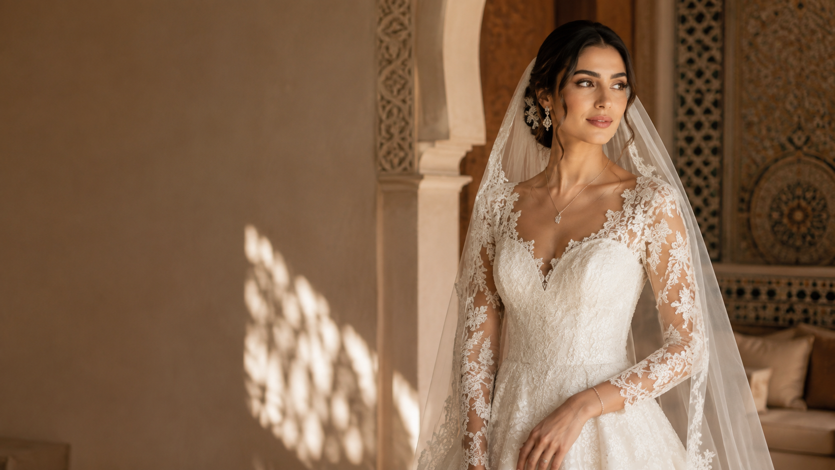 A bride in an ivory lace gown and veil photographed in a sunlit traditional Tunisian interior.